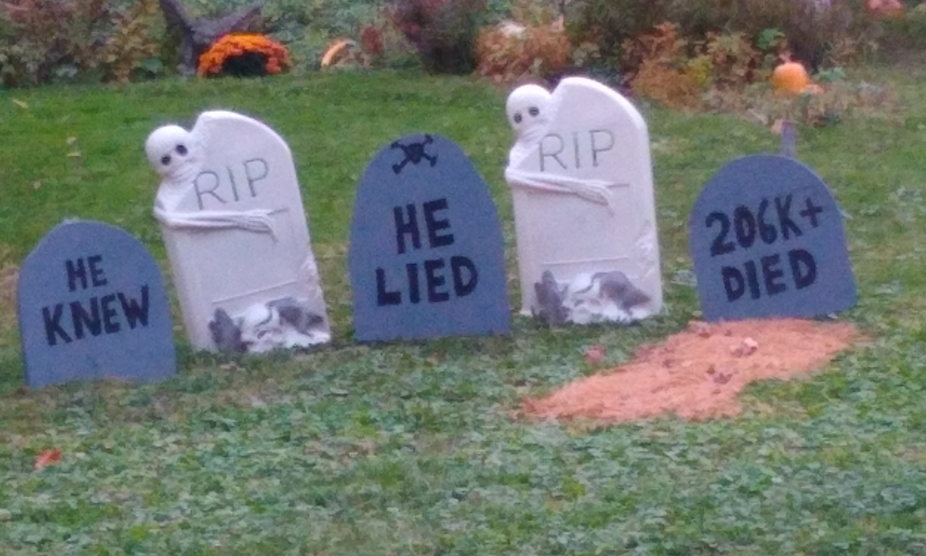Halloween-style headstone
decorations say 'he knew,' 'he lied,' and '206K died'