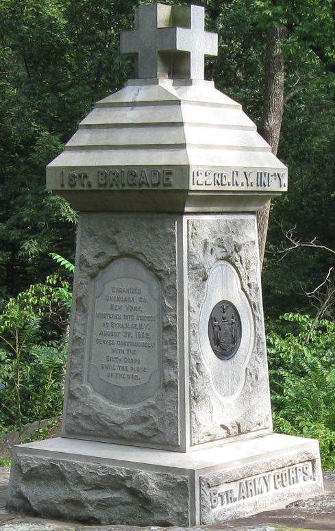 It is about 10 feet tall, with a red cross-type
cross on top (though it's not red in color); it's carved out of granite that has grown a little gray over time, and has a bronze medallion 
about the size of a small pizza on one side
