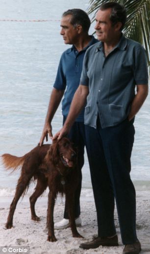 Nixon and Rebozo are dressed in
slacks, casual shirts, and are walking a dog along the beach.