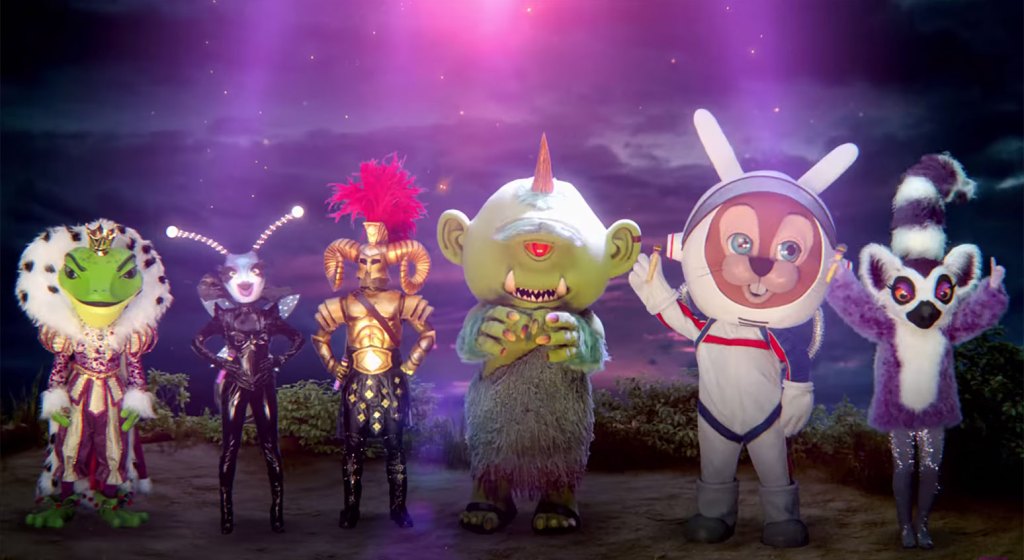 Six costumed people: a salamander in
purple king's robes, an ant with big antennae, some sort of warrior with a helmed adorned with sheep's horns, a one-eyed
green ogre with a giant head, a rodent of some sort in a space suit, and a purple koala with a tall striped top hat.