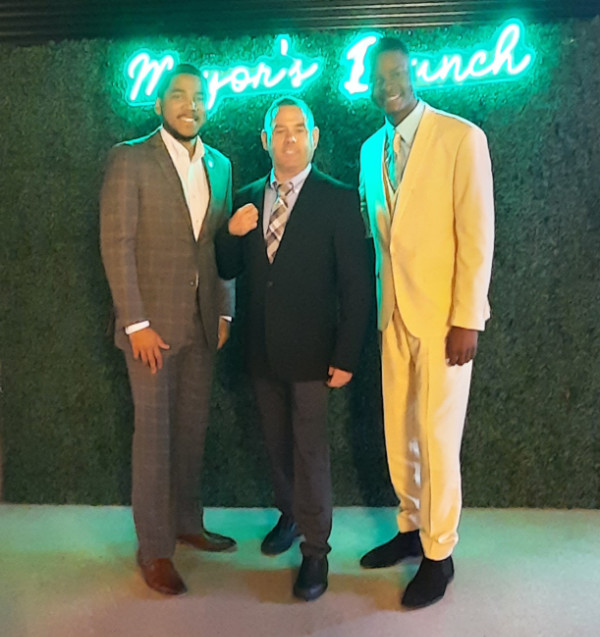 Reader B.T., flanked by the two 
mayors, all of them in suits, standing in front of a sign that says 'Mayors' lunch'