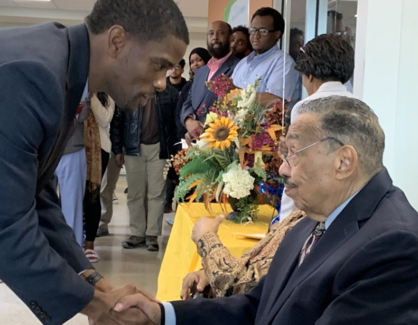 Bill Wilson sits as he shakes hands with Melvin Carter