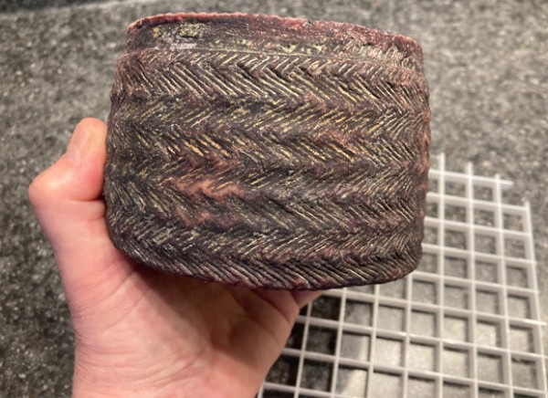 The reader is holding a softball-sized,
but cylindrical object that has an outer coating that looks like tire tracks