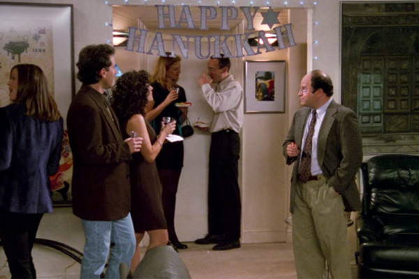 Jerry, George and
Elaine stand beneath a banner that says 'Happy Hanukkah'