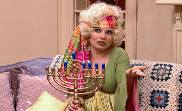Fran, dressed in 1960's garb, holds a menorah