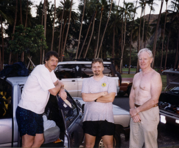 Three men, standing in a clearing,
surrounded by palm trees