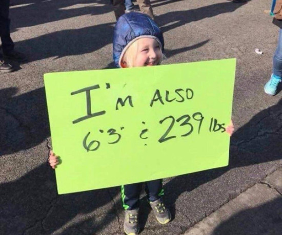 A very young girl holds a
sign that says 'I'm also 6'3 and 239 pounds
