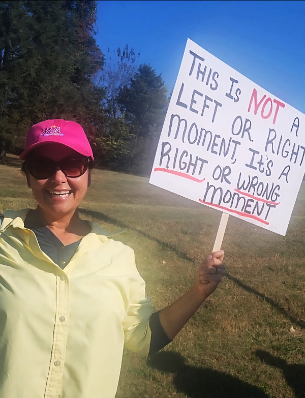 A sign says 
'THIS IS NOT LEFT OR RIGHT MOMENT, It's A RIGHT OR WRONG MOMENT'