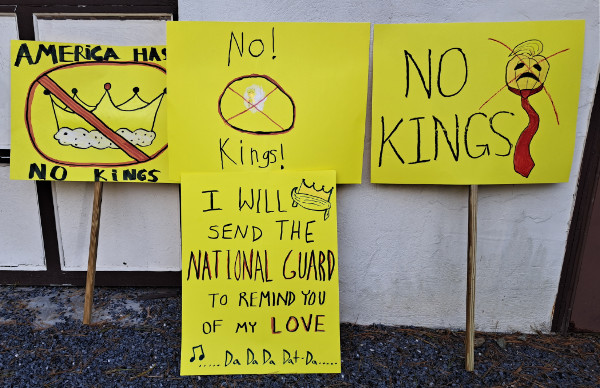 A group of 
No Kings signs on yellow posterboard