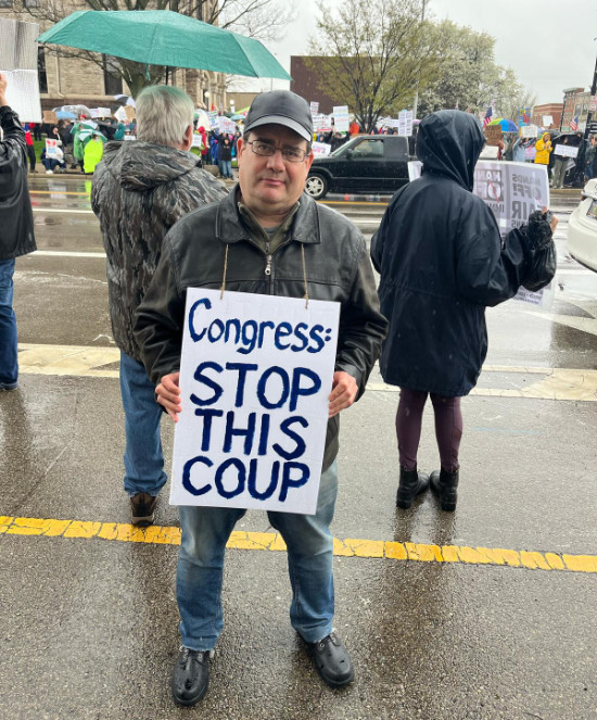 A gentleman with 
glasses holds a sign that says: 'Congress - Stop this coup'