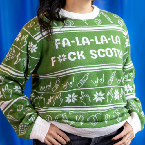 The sweater is green and white and says 'FA-LA-LA-LA F*CK SCOTUS