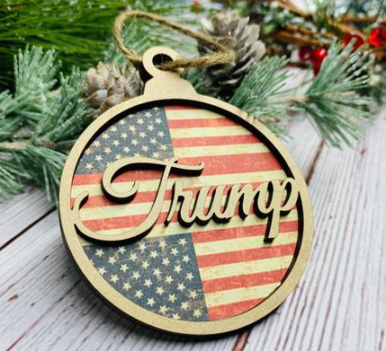 The ornament has a flag background and a cursive 'TRUMP' in the foreground