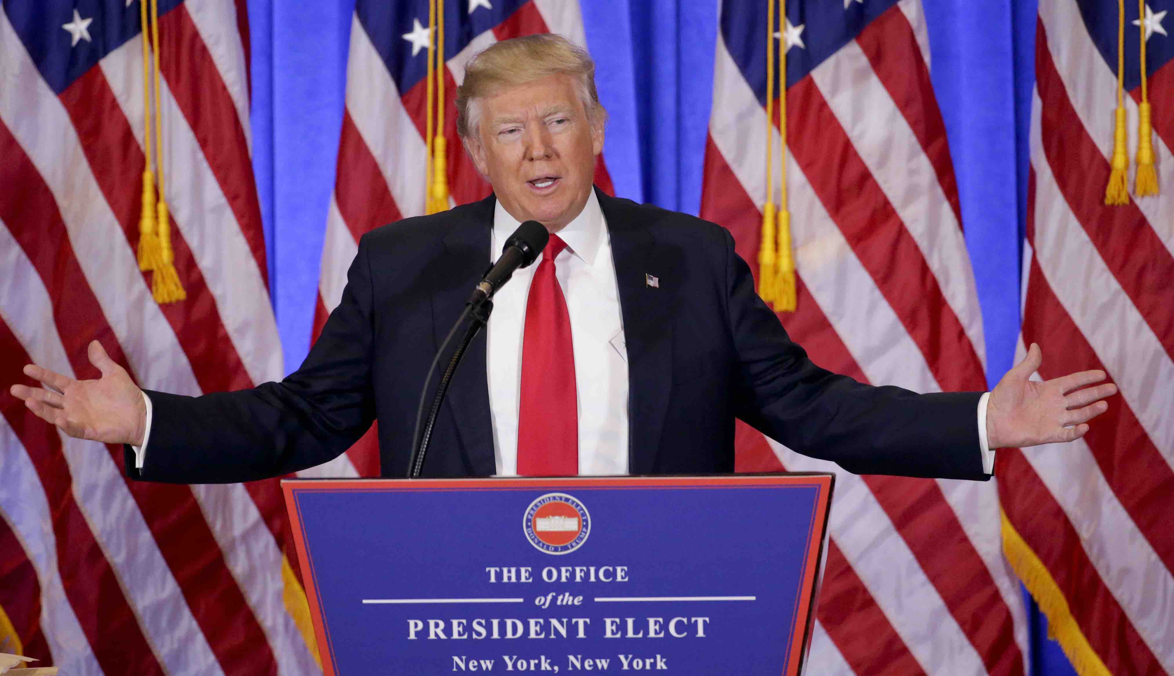 Donald Trump stands at a podium that has a fancy-looking
seal with a the White House and the text 'office of the president elect'