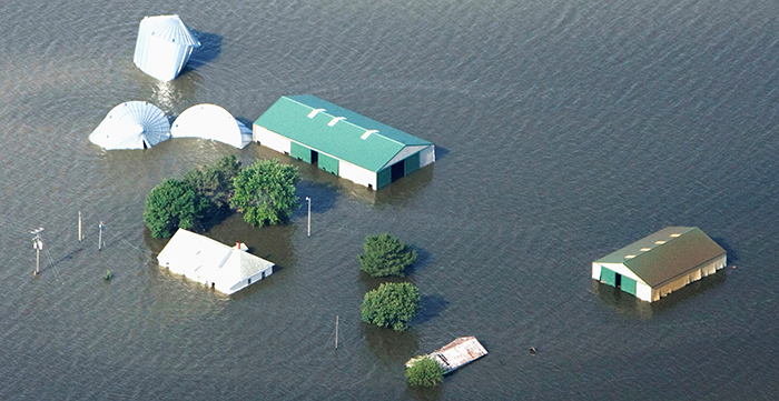 A house and several other structures
are almost completely underwater, such that you can only see their roofs.