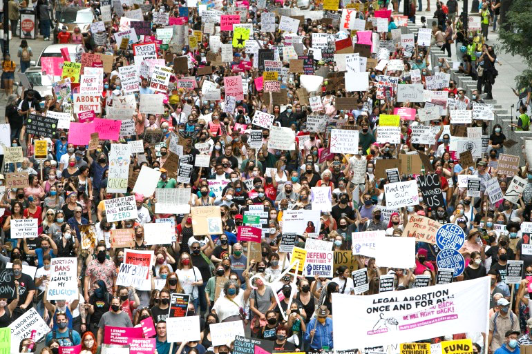 Pro-choice march in Chicago; the crowd is very large, 
at least 300 people are visible and they are spillling out of al four sides of the frame