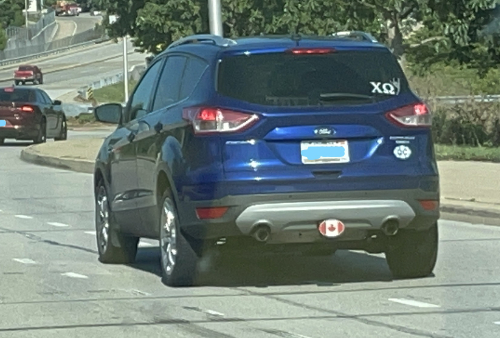 A blue SUV with an Indiana license plate,
a Canadian flag decal, and a Chi Omega decal