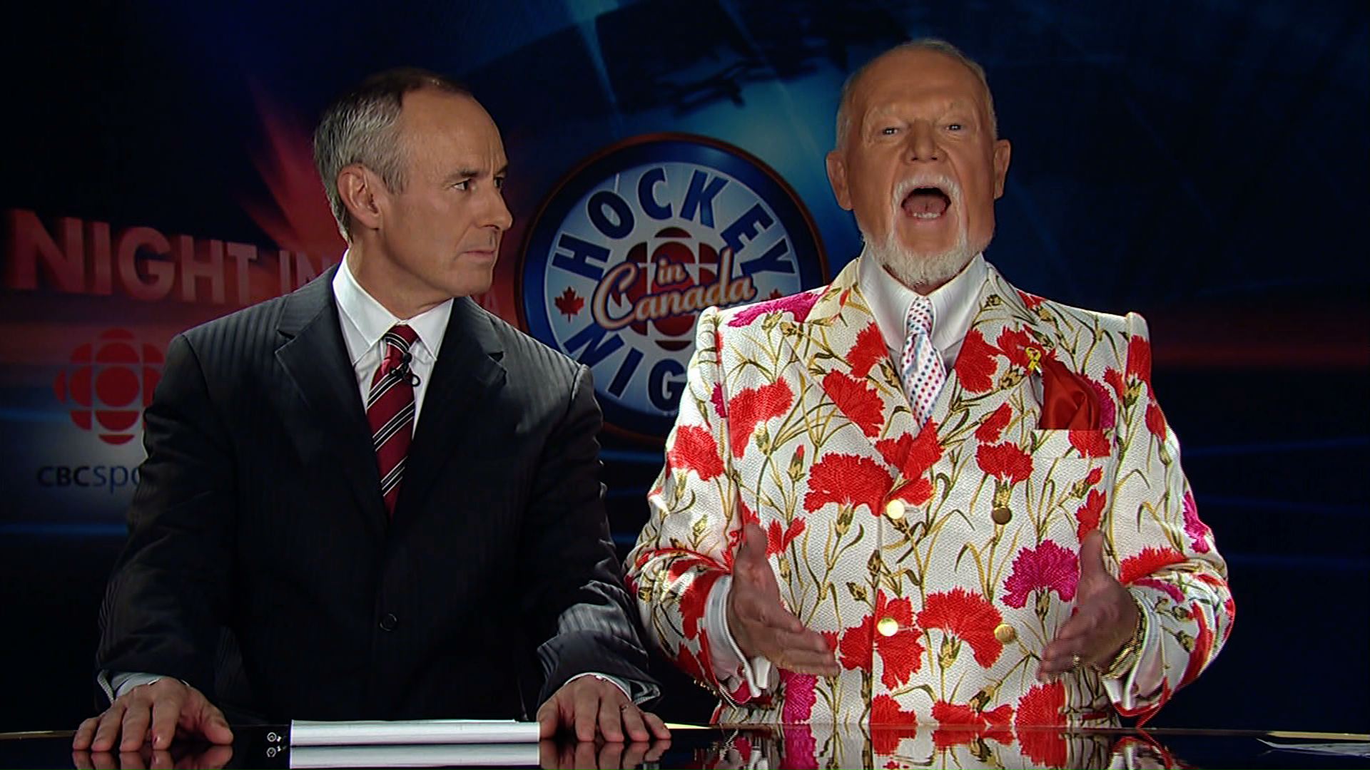 Don Cherry, who is in his 60s and has
white hair and a white goatee, wears and extremely loug rainbow-checked blazer, along with a tie that appears to show the 
aurora borealis.