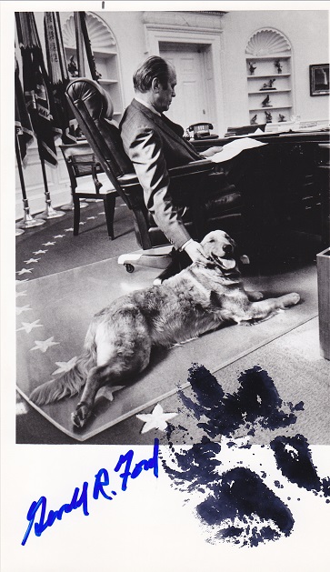 A photo of Gerald Ford in the
Oval Office, Liberty the dog on the floor with a paw print in black and Ford's signature in blue