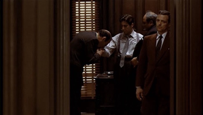 The closing shot of the
movie 'The Godfather'; the viewer watches through a doorway as a man pays fealty to Michael Corleone by kissing his hand.