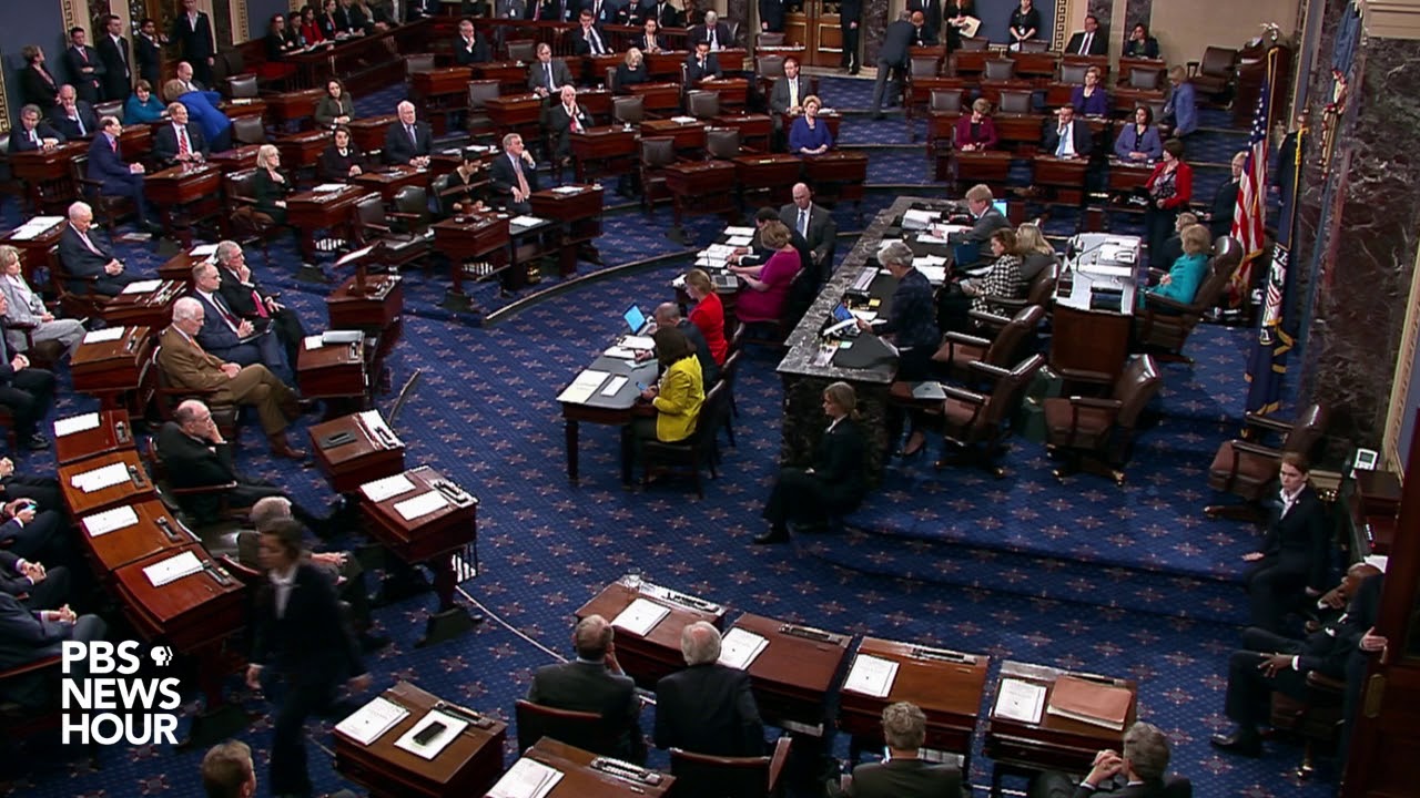 The front of the Senate floor is
shown from the side; to the right is the presiding officer's desk flanked by some chairs, in front of that is a marble desktop
with chairs that probably spans about 20 feet in total, and in front of that is a pair of 8-foot tables.