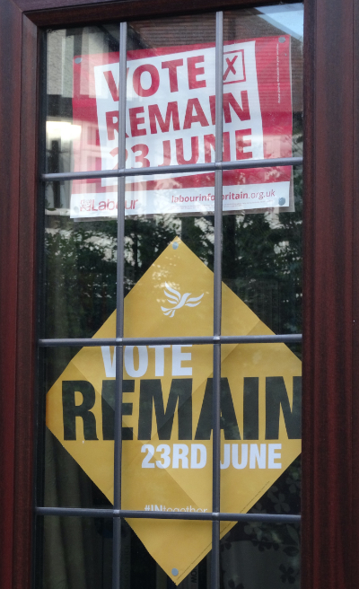 Two signs taped to the window that
is inset into a front door; the top one is red and white and has the name of the Labour Party along with 'Vote Remain - 23 June'
while the bottom one is yellow, white and black and says 'Vote Remain - 23rd June'