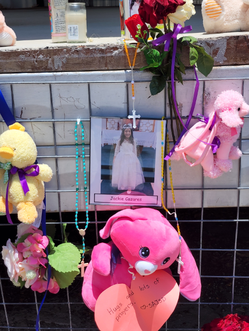 Picture of a 10-year-old in her First Communion
dress, posted on a wall outside the church, surrounded by other items, like a pink teddy bear