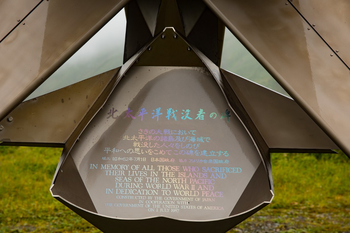 It is made of metal,
and inscribed in rainbow letters in both English and Japanese, and says 'In memory of those who sacrificed their lives 
in the islands and seas of the north Pacific during World War II and in dedication to world peace.'