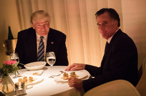 Mitt Romney and Donald Trump have 
dinner; Romney is grimacing while Trump is grinning maniacally