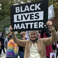 A woman holds a sign that says 'Black Lives Matter'