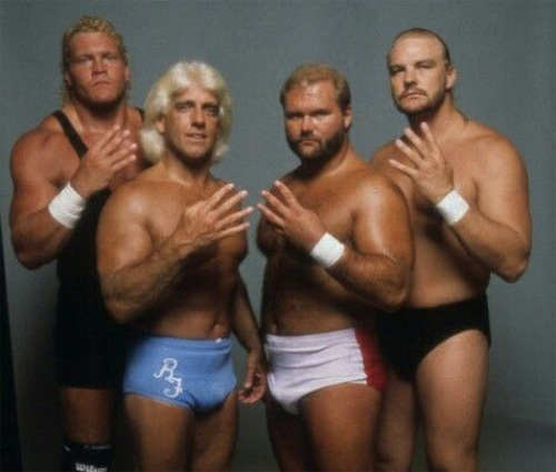 Four pro wrestlers, each holding up four fingers