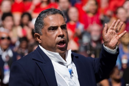 A man gives a speech with his hand raised