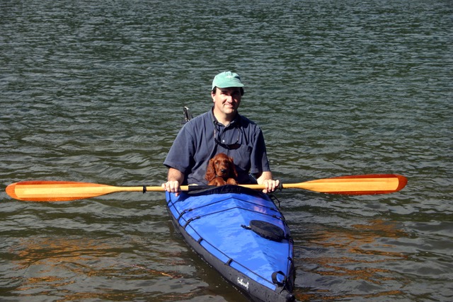 A person kayaking with a dog on his lap