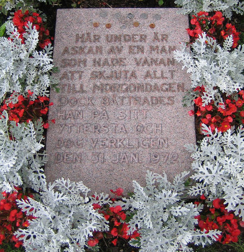 A gravestone surrounded by red 
and white flowers, and with an inscription in Swedish