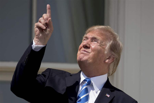 Trump squinting and pointing up at the sky