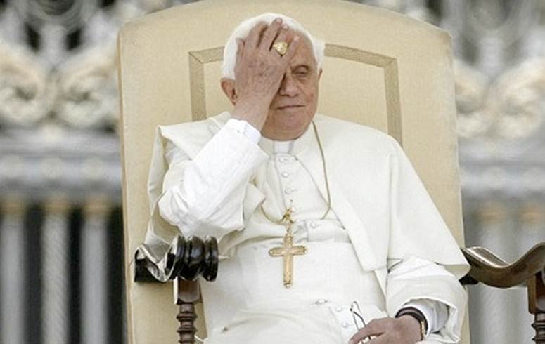 The pope holds his face in his hand while sitting on the papal throne