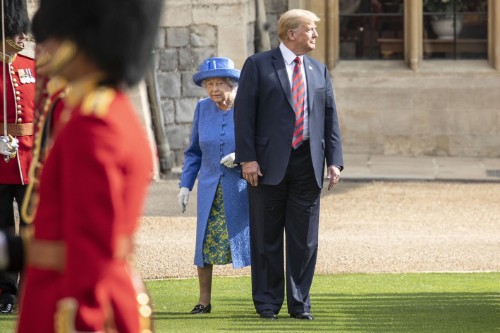 Trump stands in front of the queen as they walk together