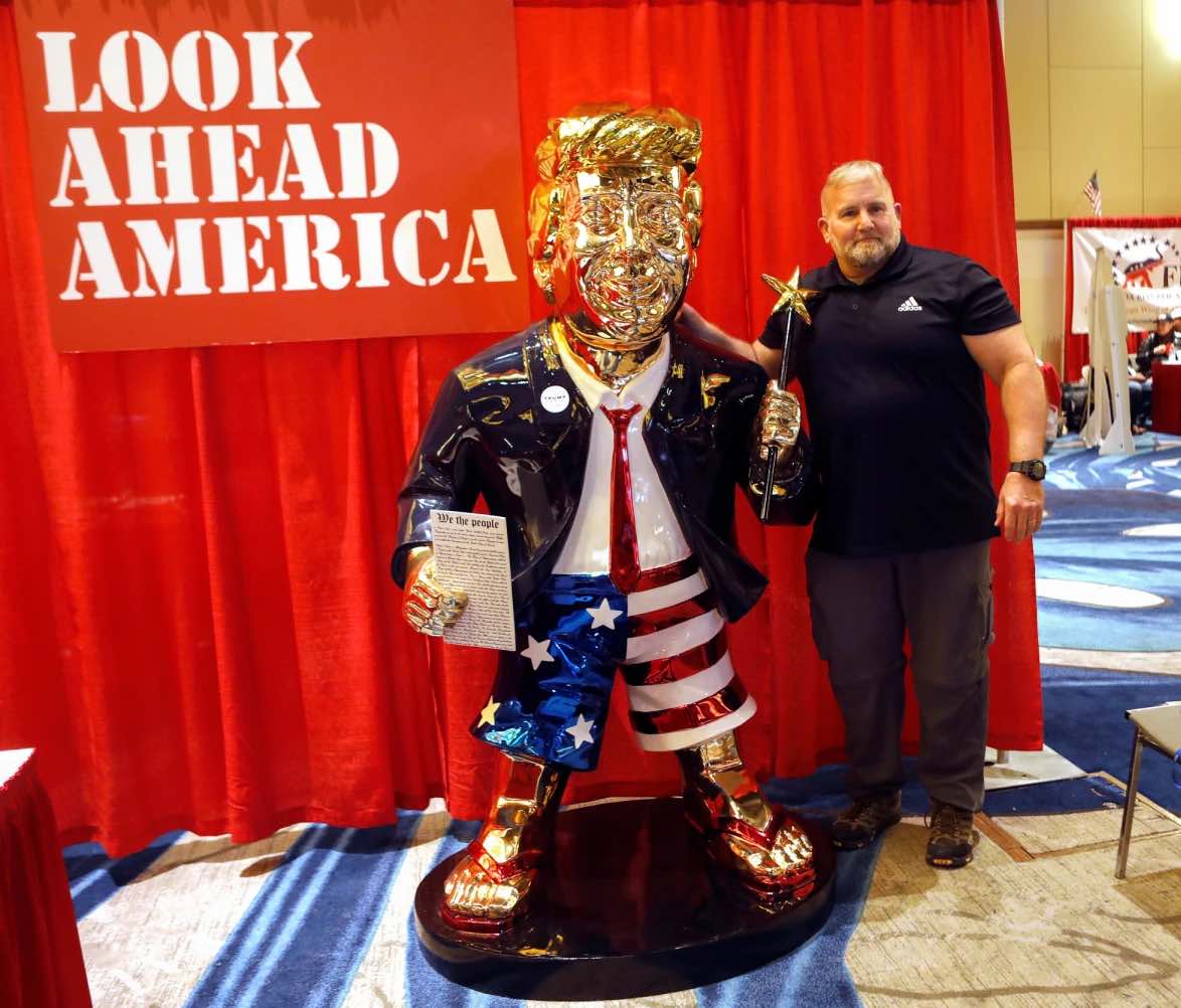 Trump supporter standing next to a full-size
golden statue of Trump