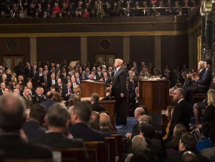 There are 30 or so members sitting in temporary chairs on each side of Trump