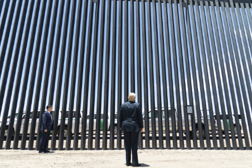 Trump stands in front of the border wall, made of steel bars