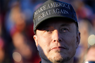 Elon Musk in a black MAGA hat
