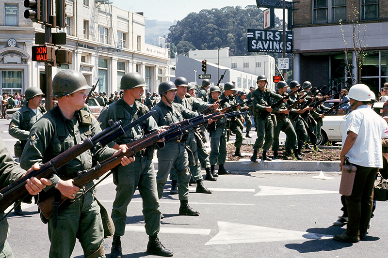National Guard occupying Berkeley, with a line of probably 20 soldiers forming a 
perimeter on the left side of the photo, and a handful of people standing around on the right side