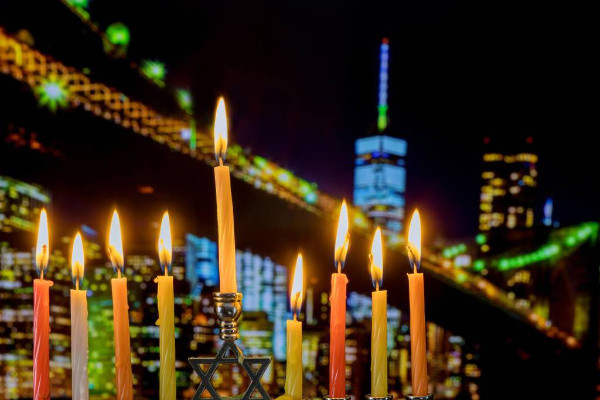 A smallish menorah; in the background is a large bridge and tall buildings