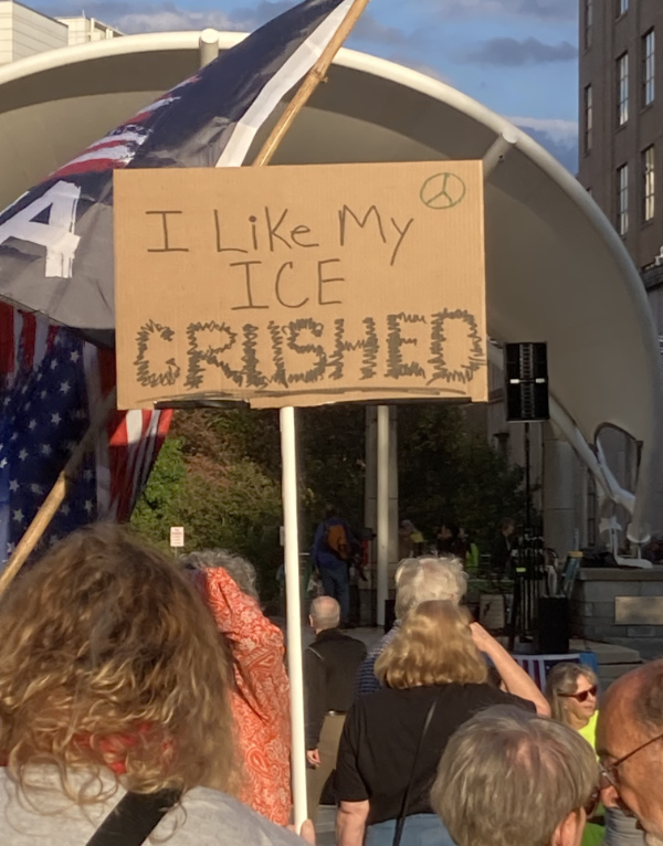 A woman holds a sign that
says 'I like my ICE CRUSHED.'