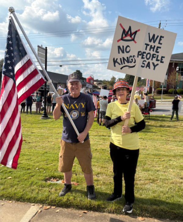 The author wears
a U.S. Navy t-shirt and waves an American flag; his mother holds a sign that says 'NO KINGS WE THE PEOPLE SAY.'