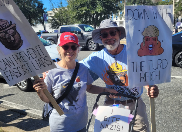 He has a sign that
says 'Down with the turd reich,' she has a sign that has Smokey the Bear and says 'Only you can prevent fascist liars'
and the dog is wearing a sign that sayd 'I bite Nazis.'