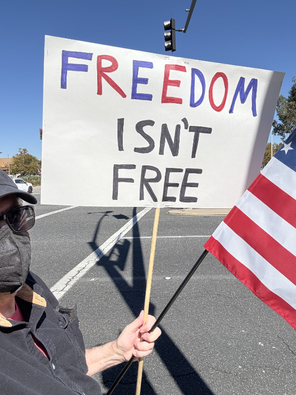 A man holds a U.S. flag
and a sign that says 'FREEDOM ISN'T FREE.'