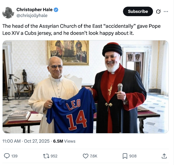 Pope Leo holds
a Cubs jersey with his name on it, standing next to a man who is clearly a high-ranking member of a non-Catholic
church, and is wearing lush black and red robes and a big cross. Leo is grimacing/smiling, the other man is
smiling, and the text of the tweet says 'The head of the Assyrian Church of the East 'accidentally' gave Pope 
Leo XIV a Cubs jersey, and he doesn't look happy about it.