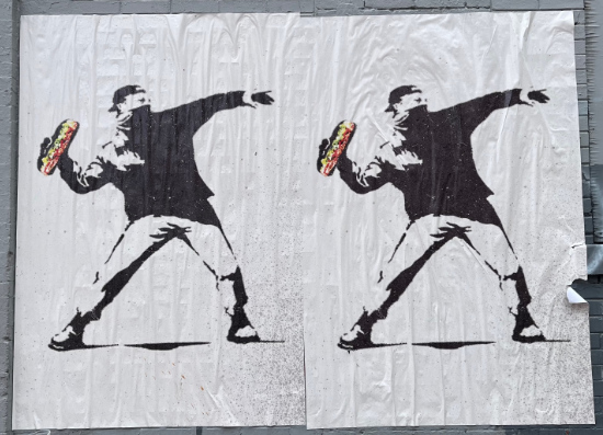 A view, from the side, of a
man with a bandanna mask, throwing a submarine sandwich. The entire image is black and white, except the sandwich, which
is colorized