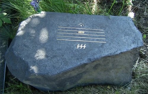 A rock with an embossed image made up of five parallel lines with 
some symbols above and an fff below
