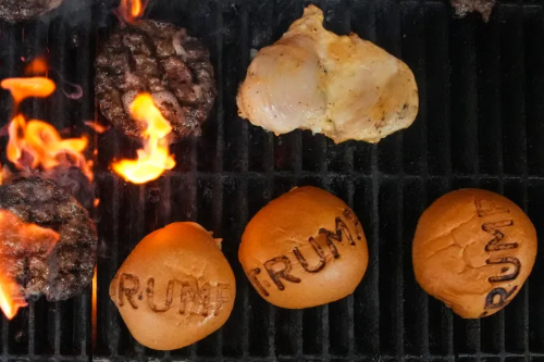 A charcoal grill, with
a couple of hamburger patties, and burger buns with a 'TRUMP' grill mark on them